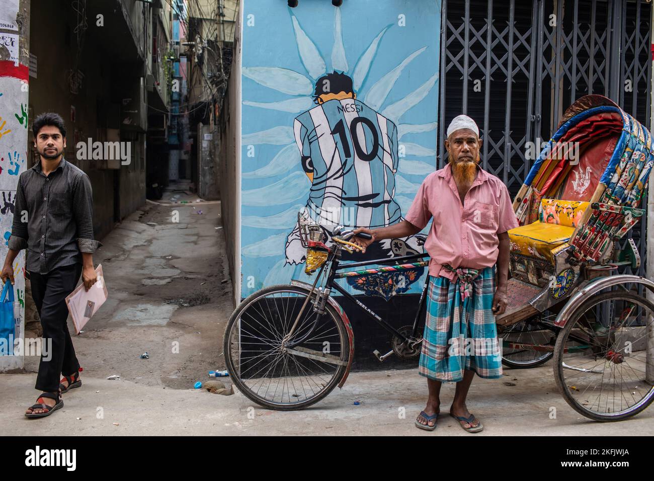 A rickshaw puller poses in front of a graffiti of famous Argentine ...