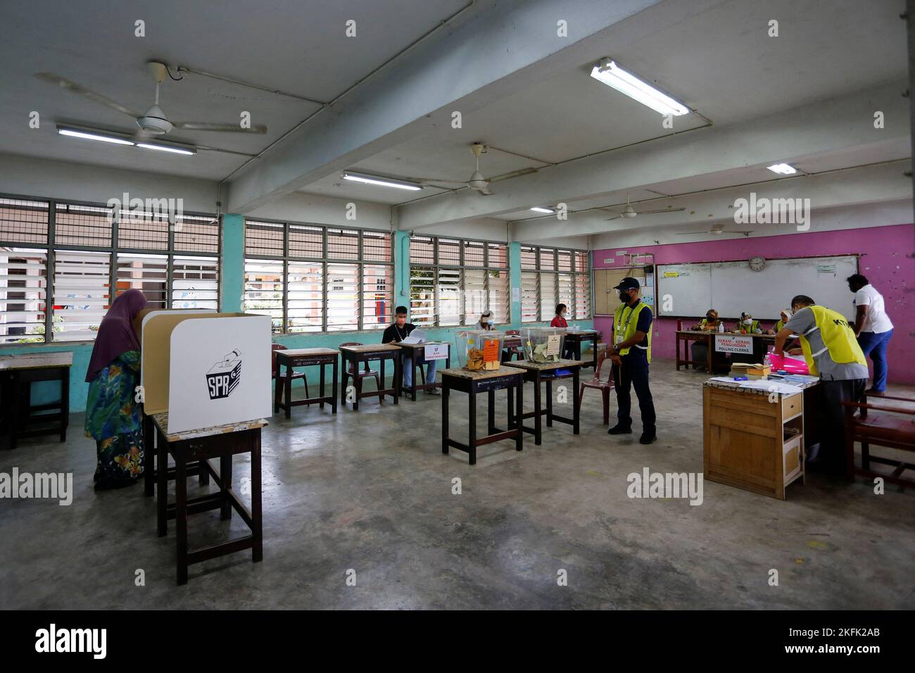 A view of a polling station as a woman casts her vote during Malaysia's 15th general election in Bera, Pahang, Malaysia November 19, 2022. REUTERS/Lai Seng Sin Stock Photo