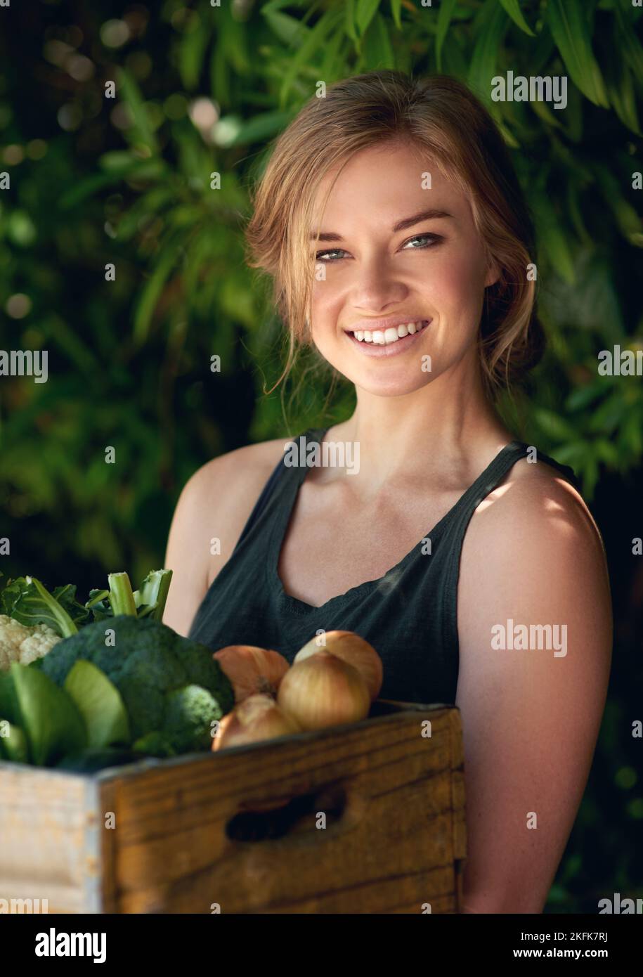 Go organic. A young woman holding a crate of vegetables outdoors Stock ...