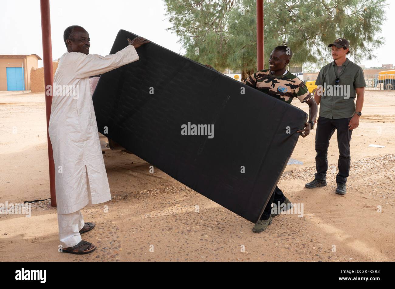 AGADEZ, Niger - Rhissa (left), Agadez Mining School (AMS) superintendent, accepts five donated mattresses from Adjutant Nadare (right), Niger Armed Forces - Affair Civil Militaire (FAN ACM) during a visit to the school in Agadez, Niger, Sept. 22, 2022. The ACM and the 443rd Civil Affairs Battalion donated five twin-size mattresses to allow students to stay at the school compound throughout the week to alleviate travel to and from home. Stock Photo