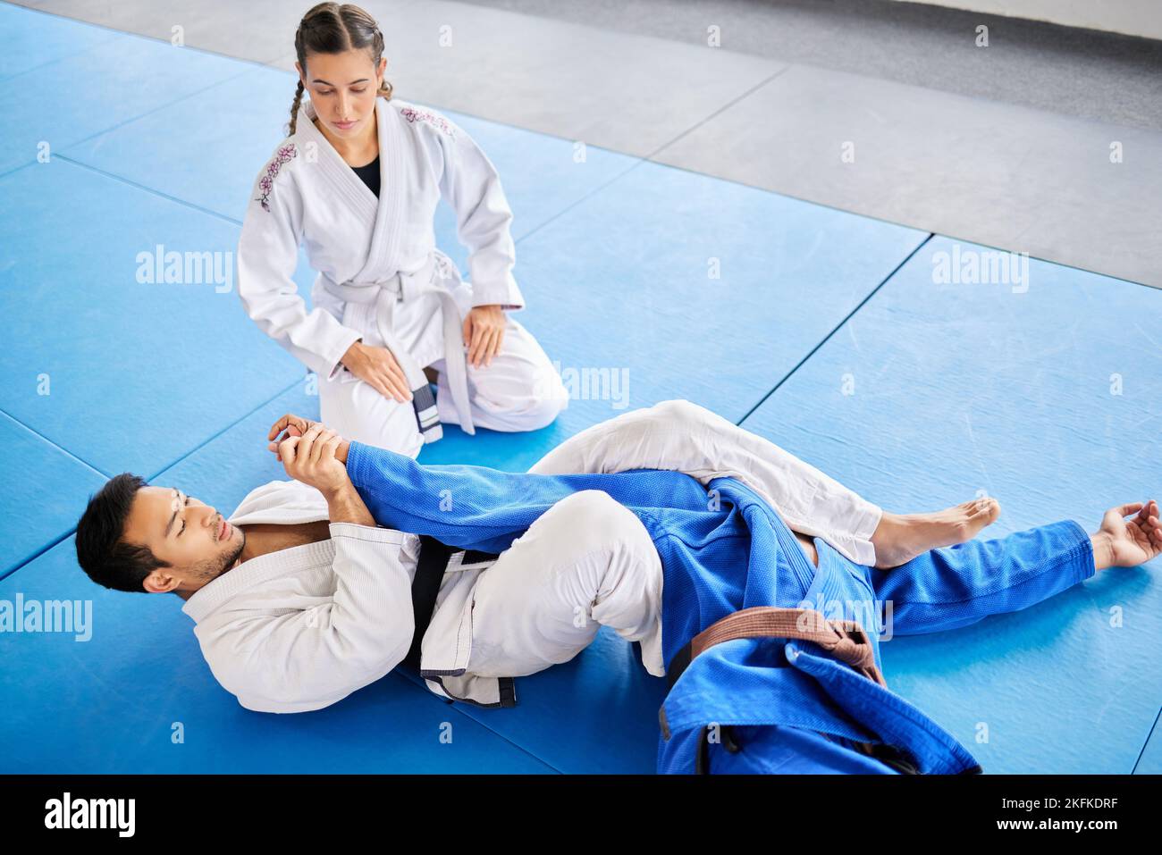 Karate, personal trainer and self defense training in the dojo for physical protection or health and safety. Black belt sensei man teaching woman to Stock Photo