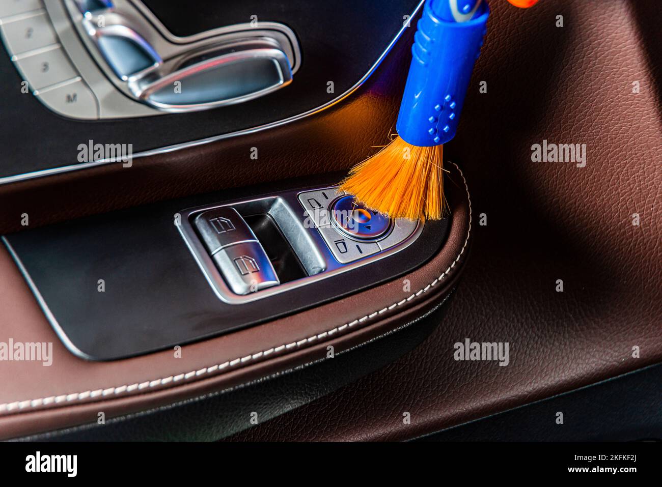 A man cleaning car interior panels and dashboard with a brush. Car