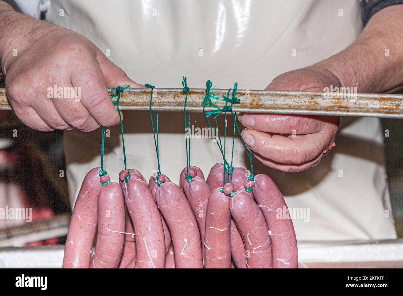 butcher prepares cooked sausages for the drying process in Germany ...