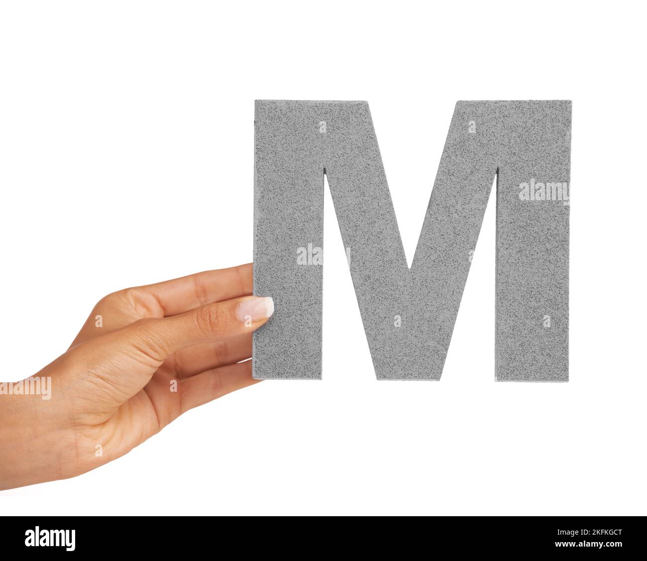 Presenting you the letter M. A young woman holding a capital letter M isolated on a white background. Stock Photo