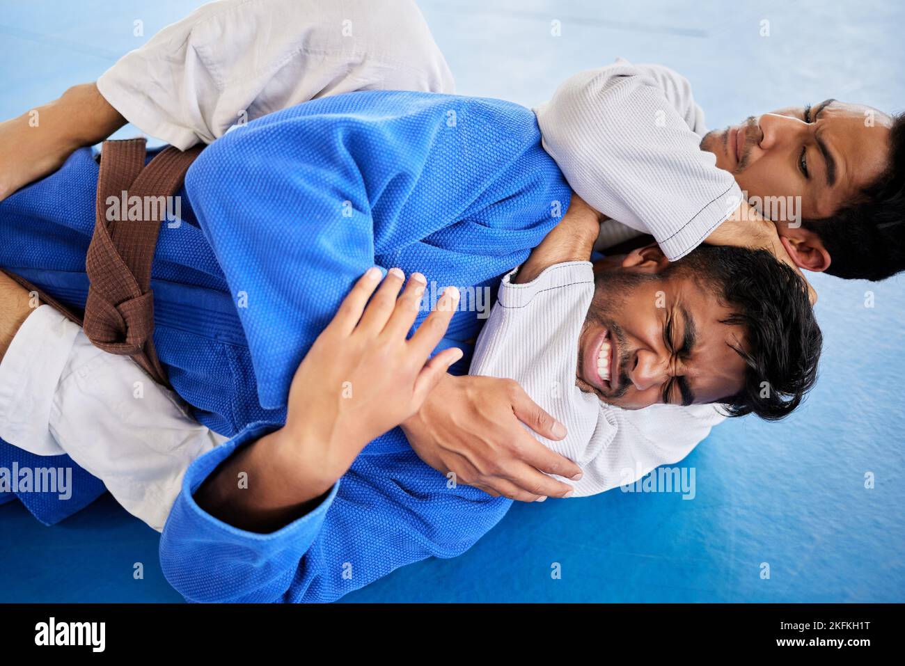 Men, martial arts and karate choke hold in dojo to practice fighting skill. Training, taekwondo and fitness class for self defense, workout or Stock Photo