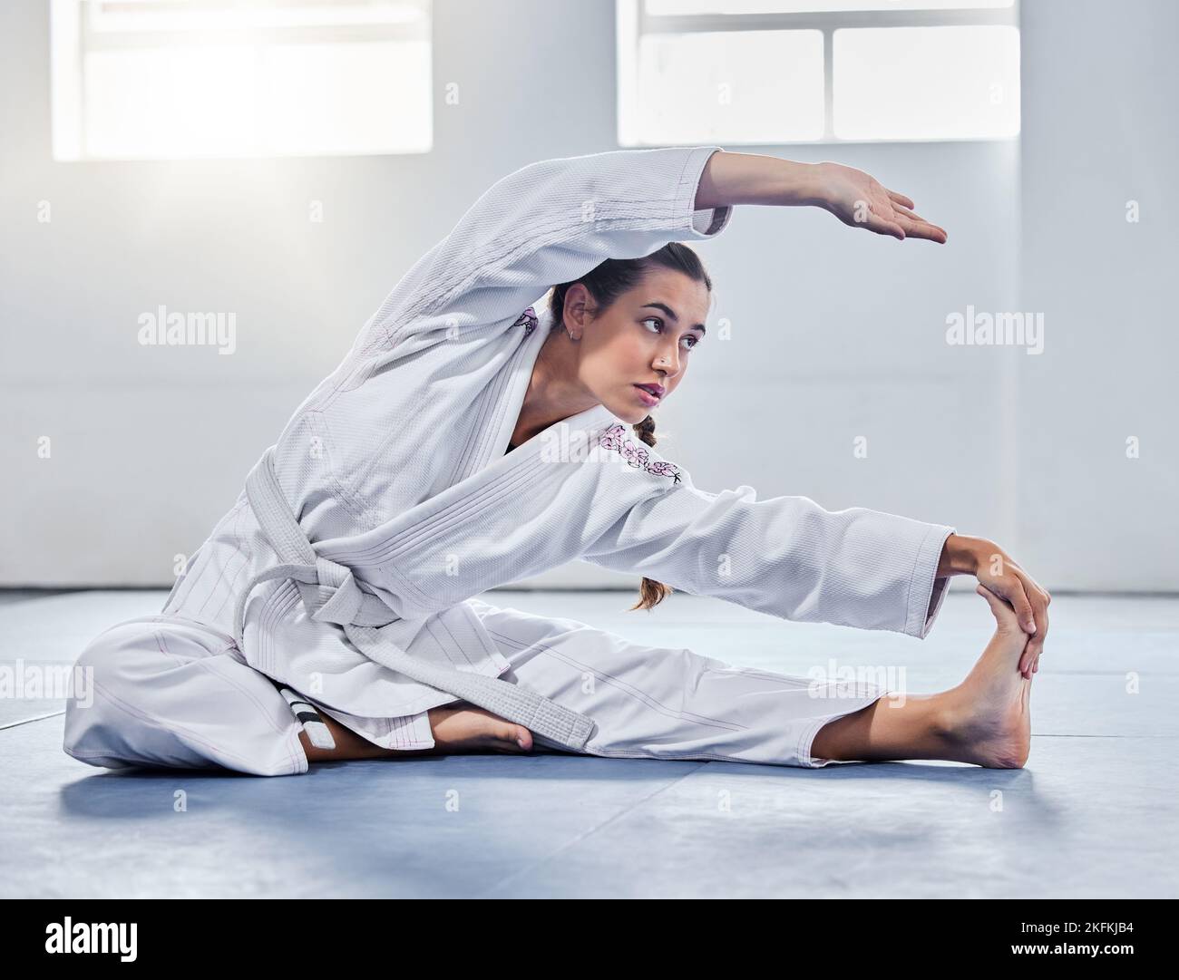 Martial arts, karate or woman stretching before training practice, fitness workout or challenge competition. Girl, warrior or taekwondo fighter warm Stock Photo