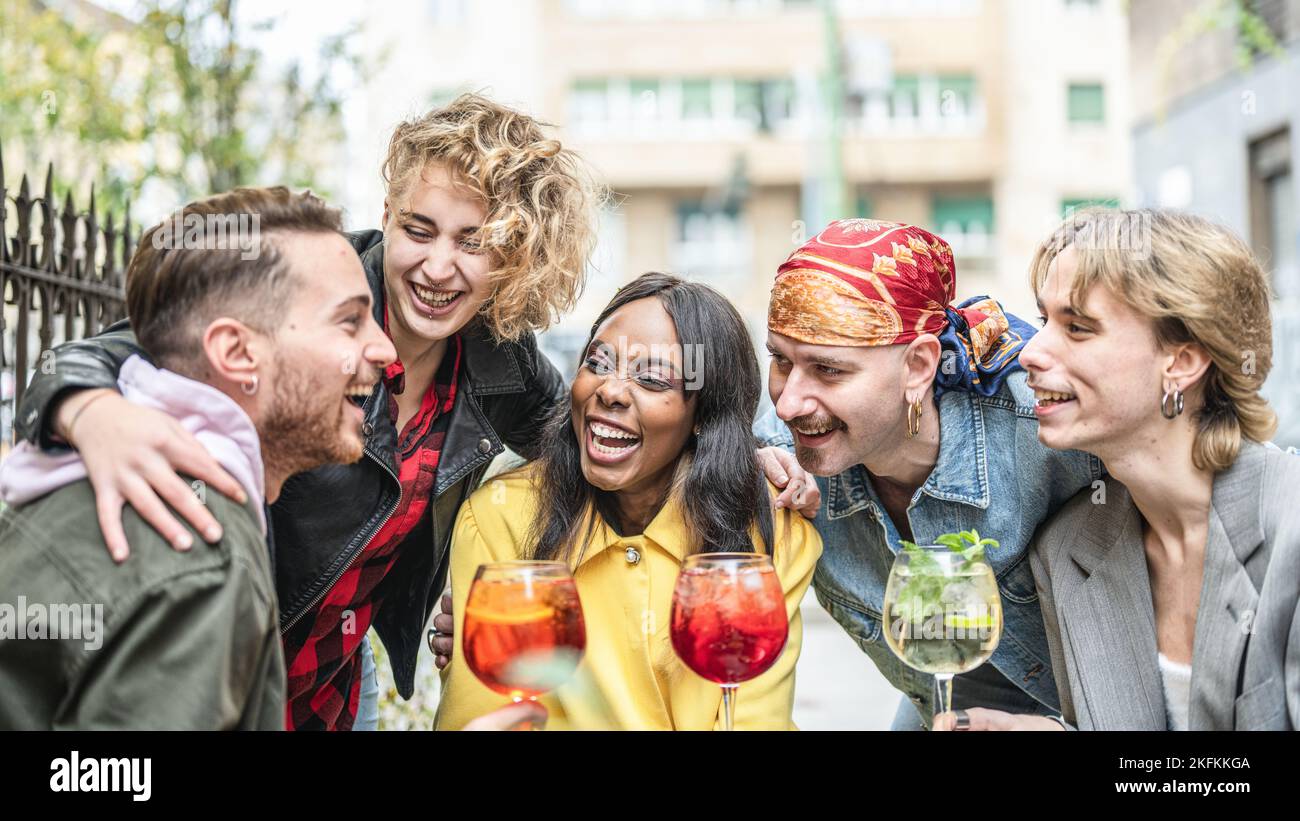 group of multiracial people toasting drinks at cocktail bar, friends ...