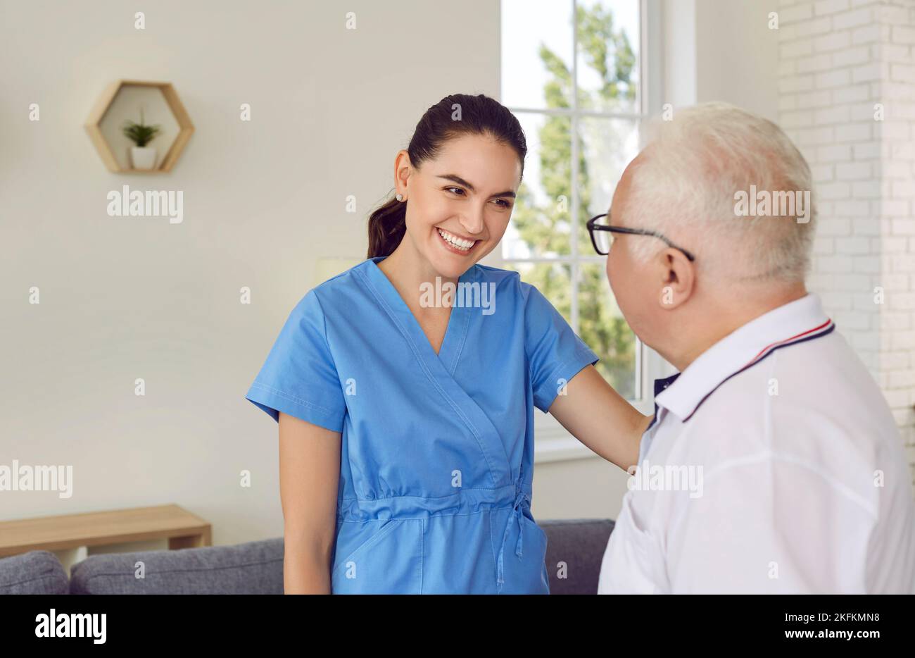 Friendly Nurse Caregiver Smiling Young Woman Is Supporting And Helping Old Man In Modern 