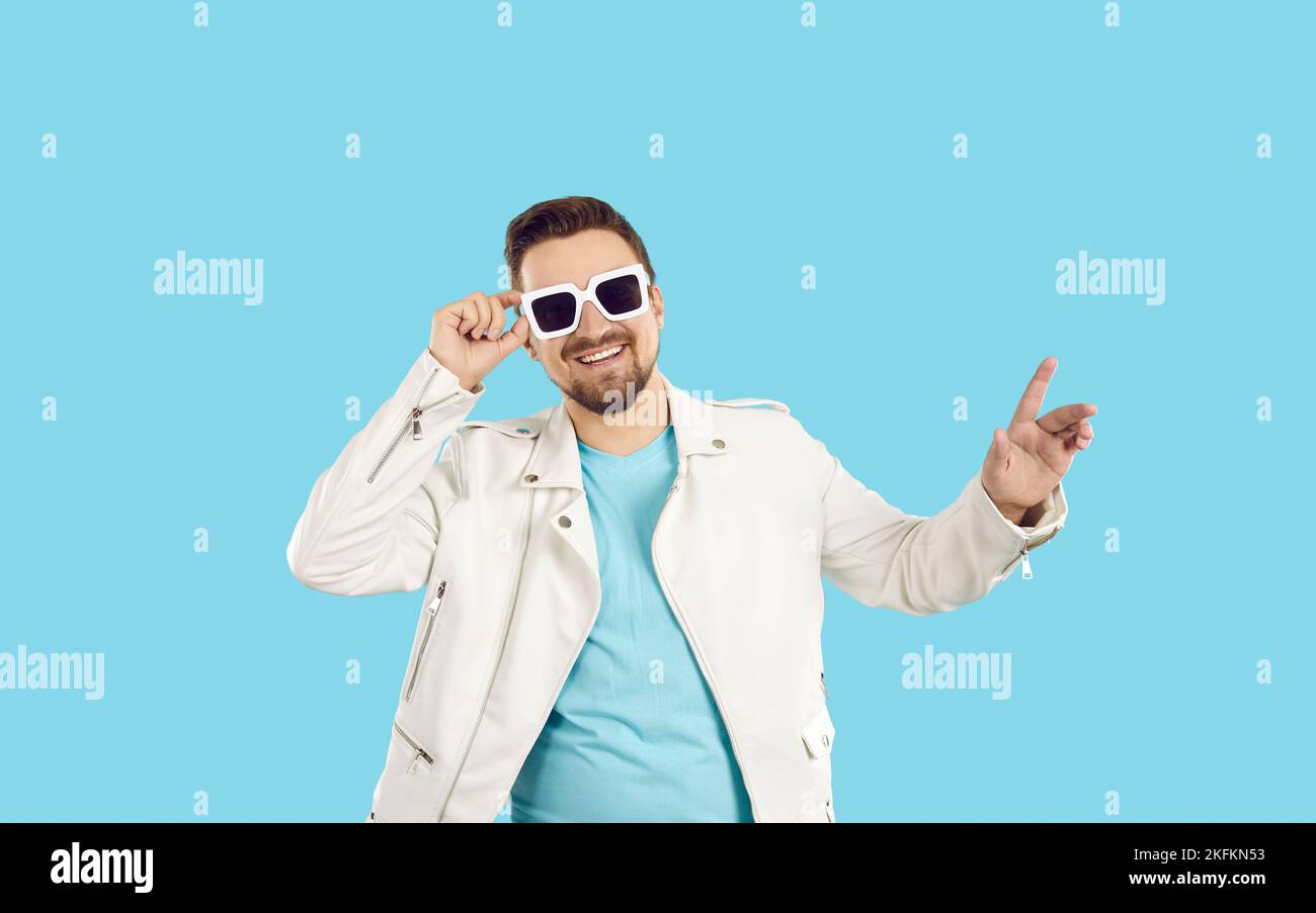 Studio portrait of happy handsome young man in white leather jacket and sunglasses Stock Photo