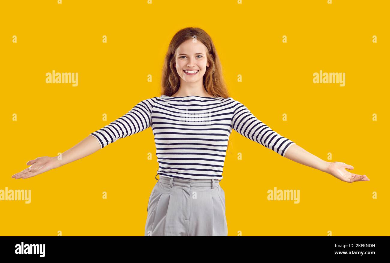 Portrait of a happy, friendly woman smiling and spreading her arms wide open for a hug Stock Photo