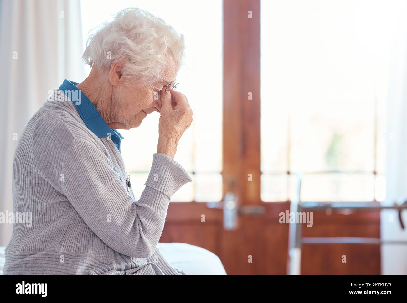 Senior woman, headache and stress with anxiety in retirement house, lonely and sad with mental health. Elderly female, depression and frustrated with Stock Photo