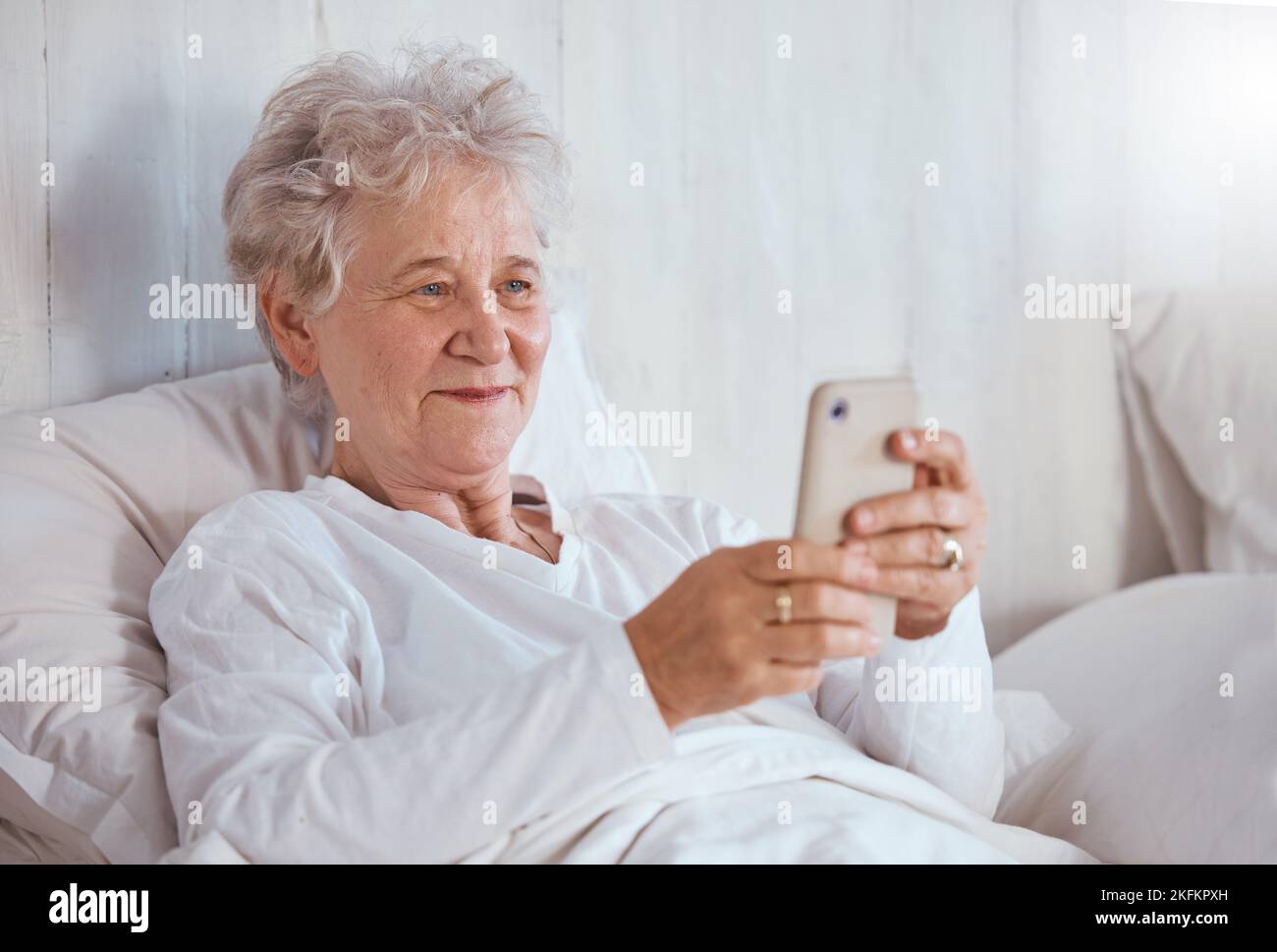 Bed, phone and relax senior patient search internet, web or online for subscription movie, show or entertainment. Healthcare, elderly care and old Stock Photo