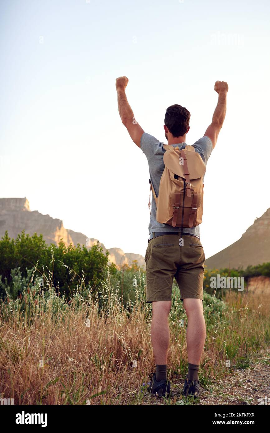 Conquering the outdoors. a handsome young man standing with his arms