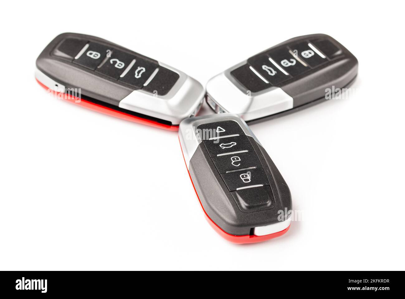 Car keys lie in different poses on a white background. Black and red car alarm key fobs are