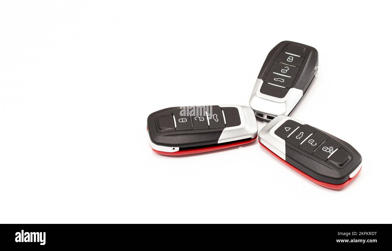 Car keys lie in different poses on a white background. Black and red car alarm key fobs are