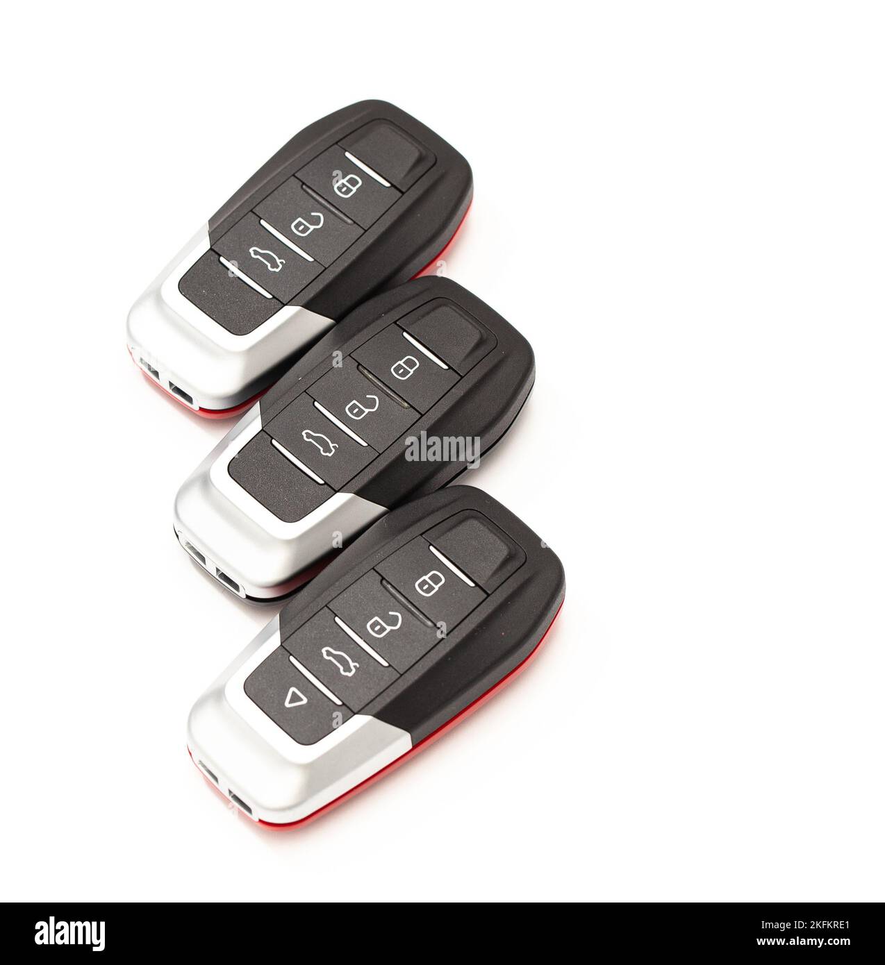 Car keys lie in different poses on a white background. Black and red car alarm key fobs are