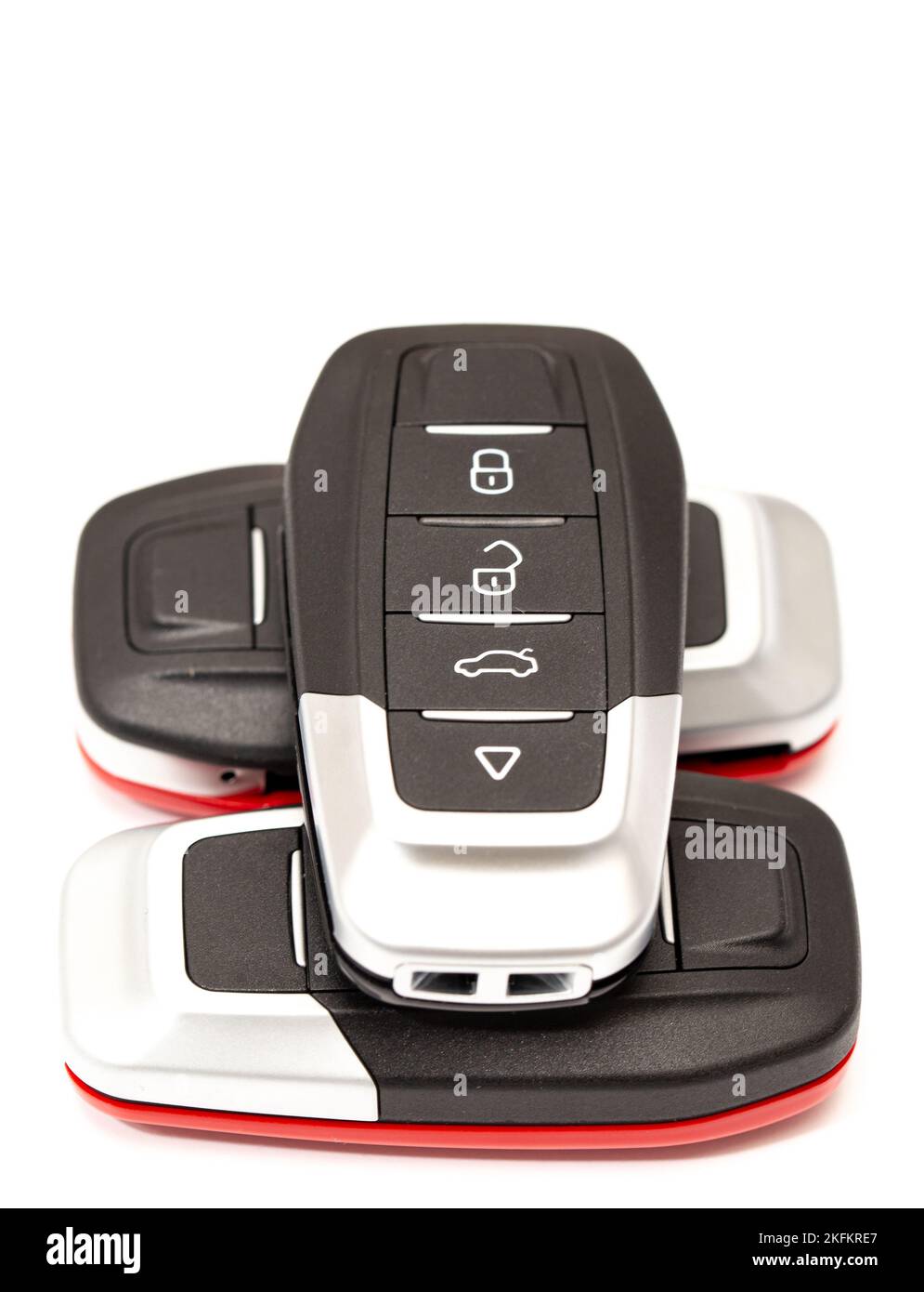 Car keys lie in different poses on a white background. Black and red car alarm key fobs are