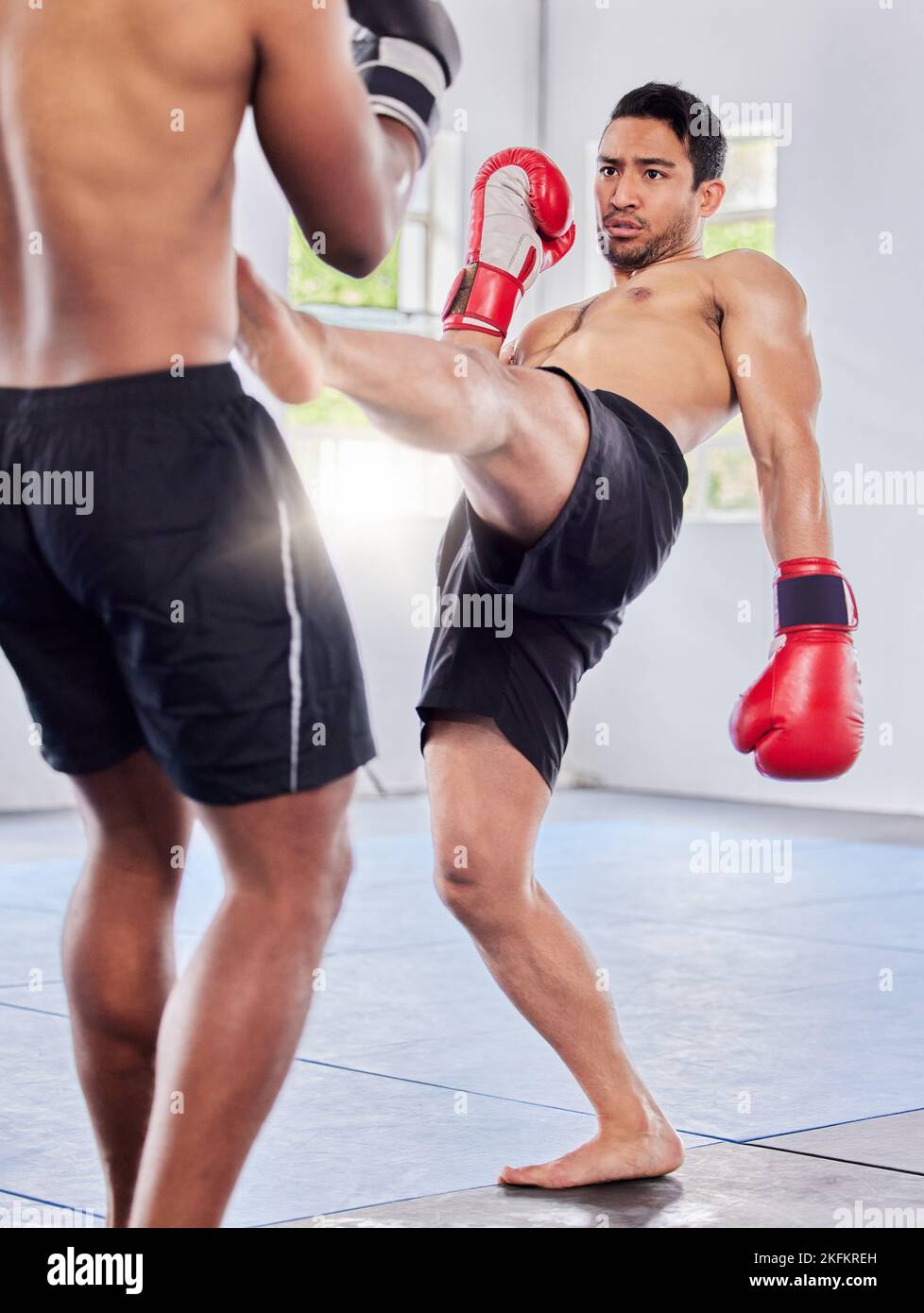 Fitness, kickboxing and mma training, exercise and fight workout in gym with men, gloves and power kick. Fight, athlete or martial arts, coaching or Stock Photo