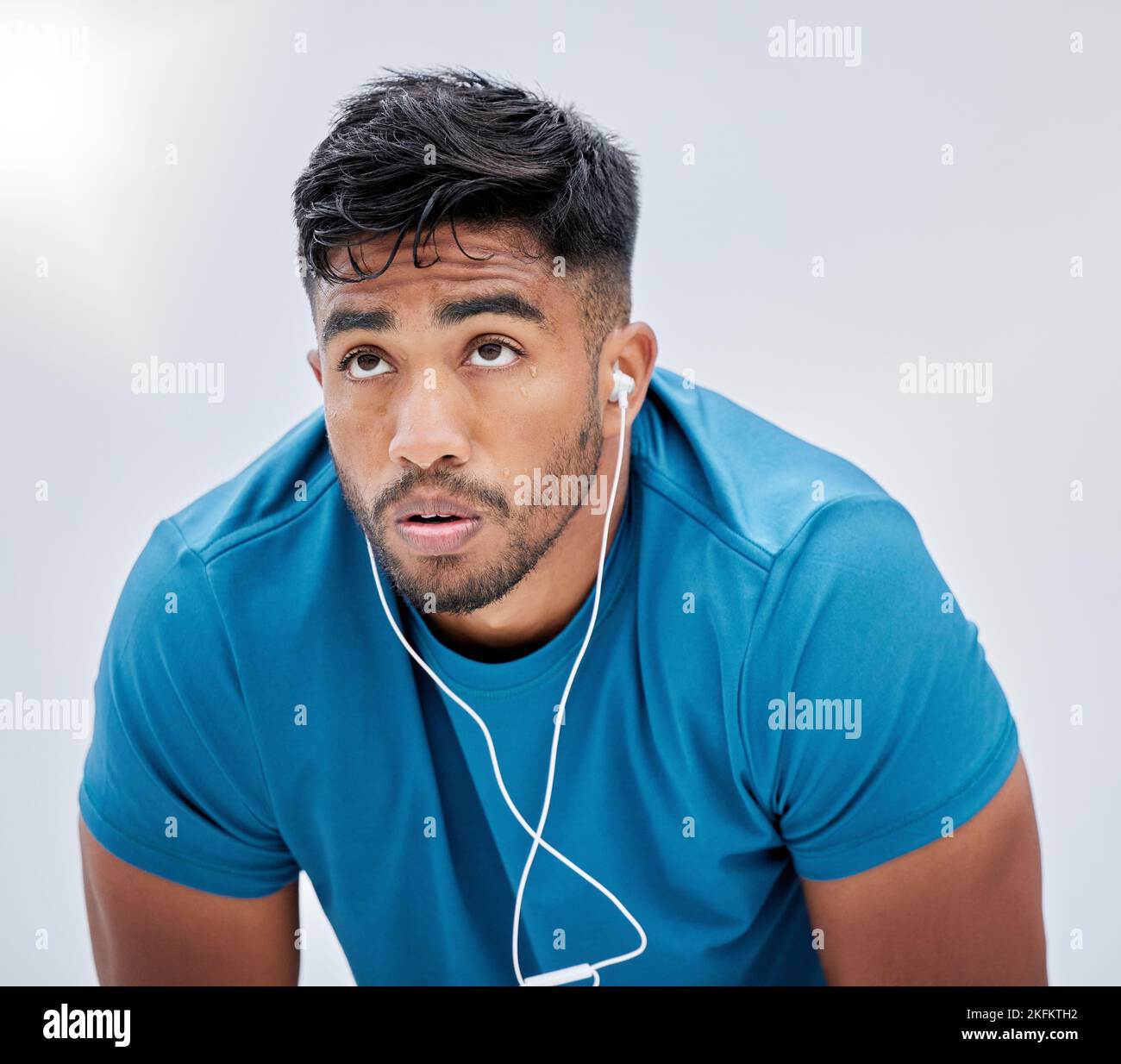 Runner, fitness and tired with a sports man sweating in studio on a gray background for health or cardio. Exercise, running and exhausted with a male Stock Photo
