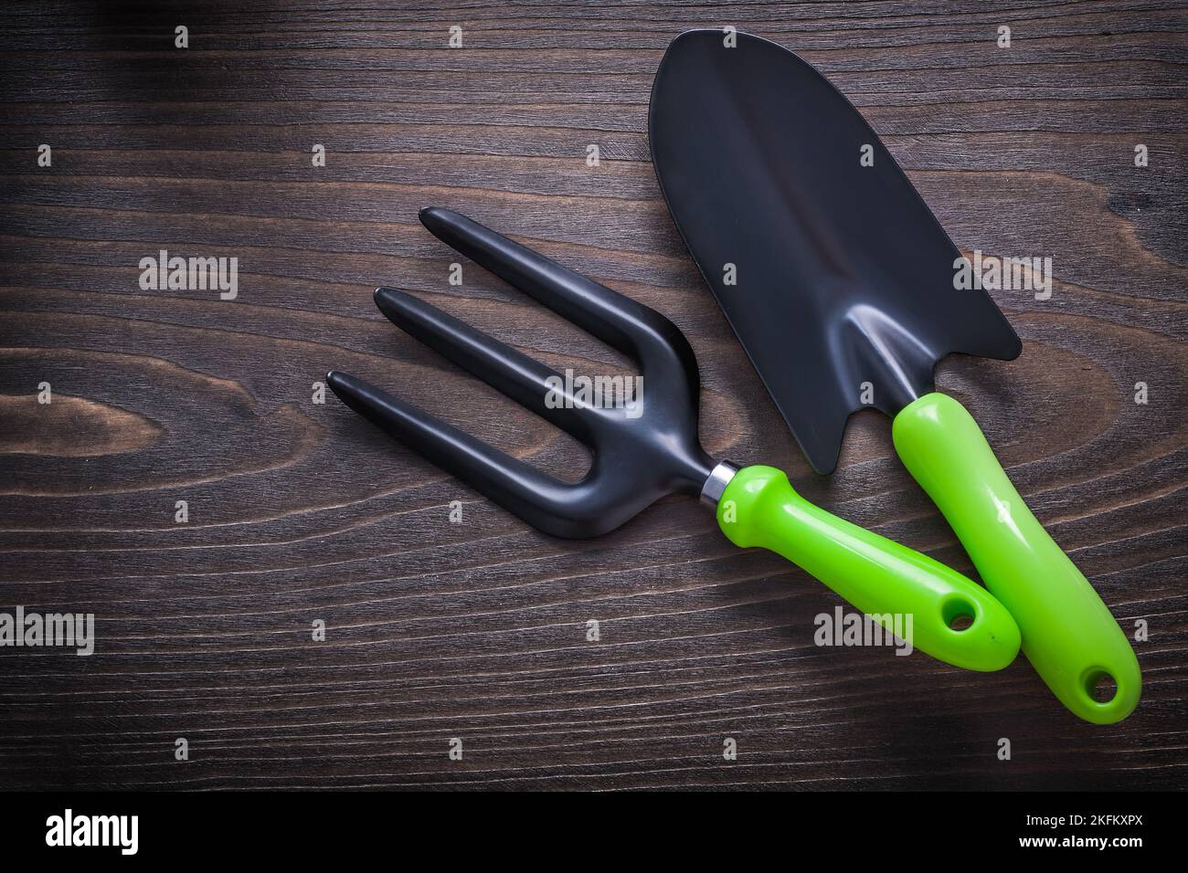 Black hand spade and trowel fork with green handles on vintage wooden