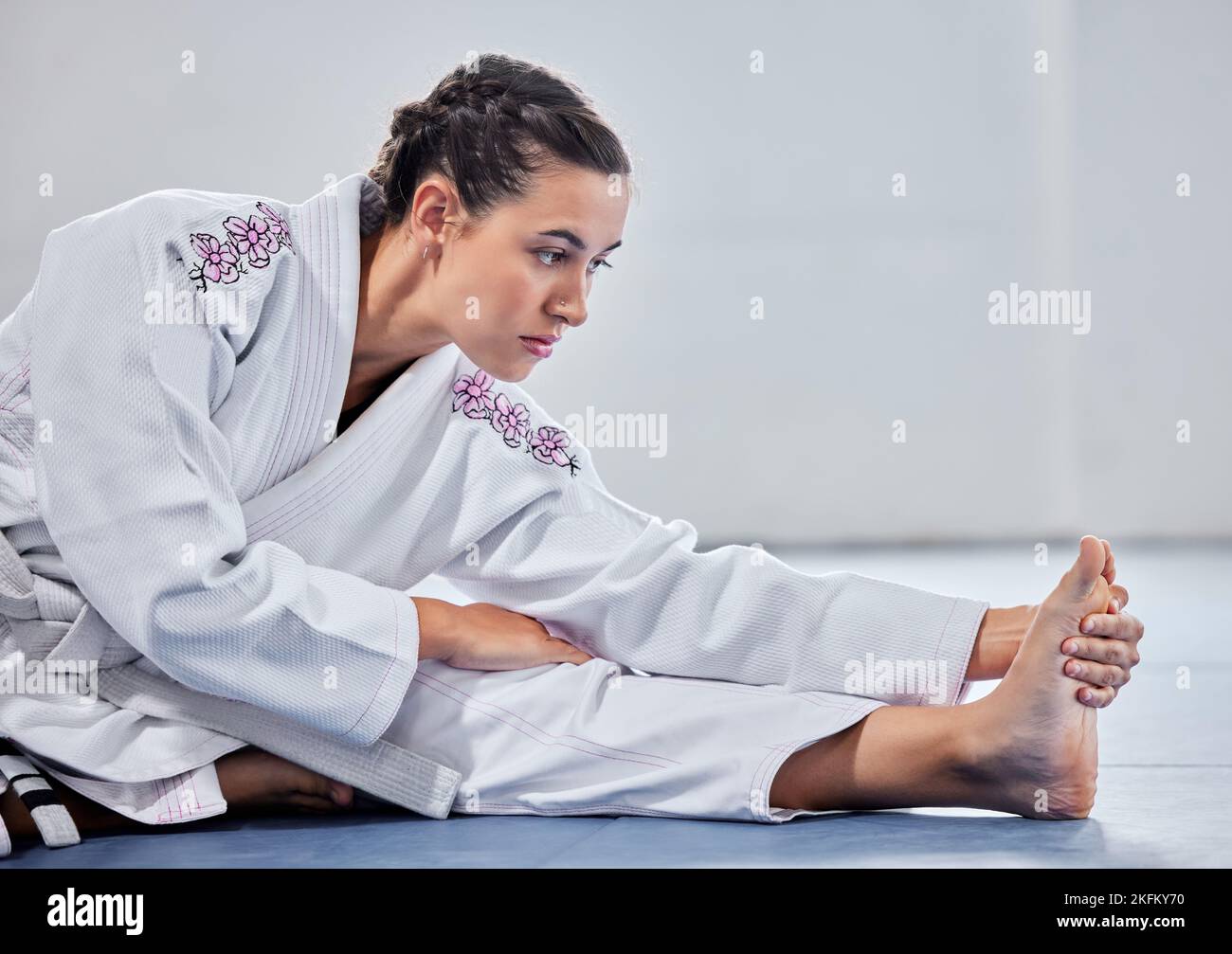 Martial arts, fitness and stretching with woman in karate school for training, sports and fight performance. Strong, focus and warm up with girl Stock Photo