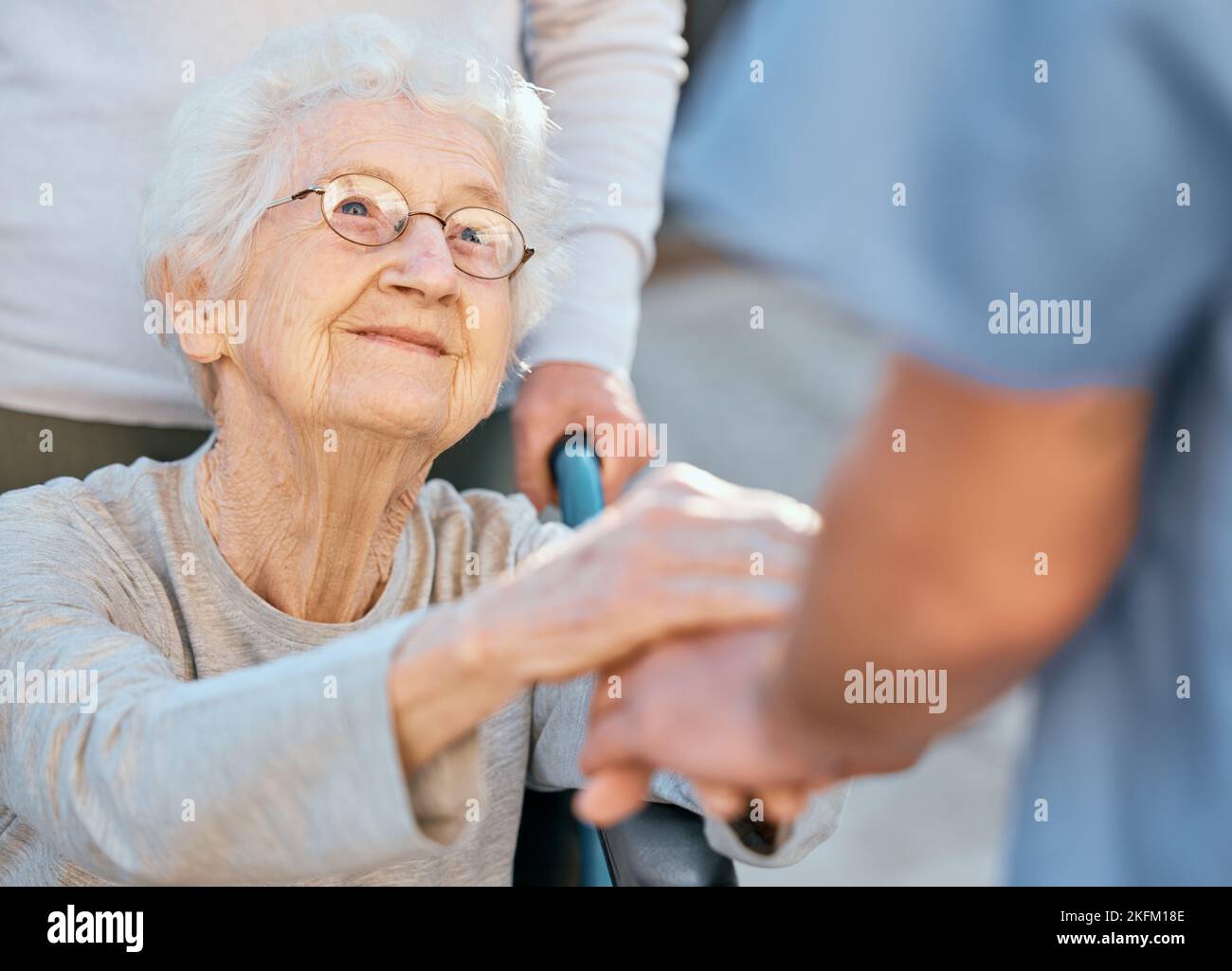 Holding hands, caregiver and senior woman in wheelchair for support
