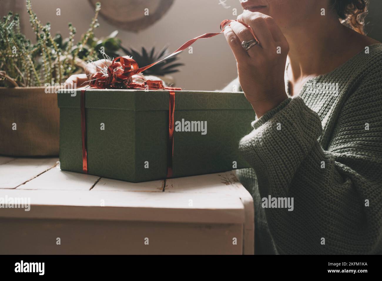 Close up of a woman unpacking a surprise gift box. Christmas or birthday anniversary present. Female people celebrate at home with a package and red t Stock Photo