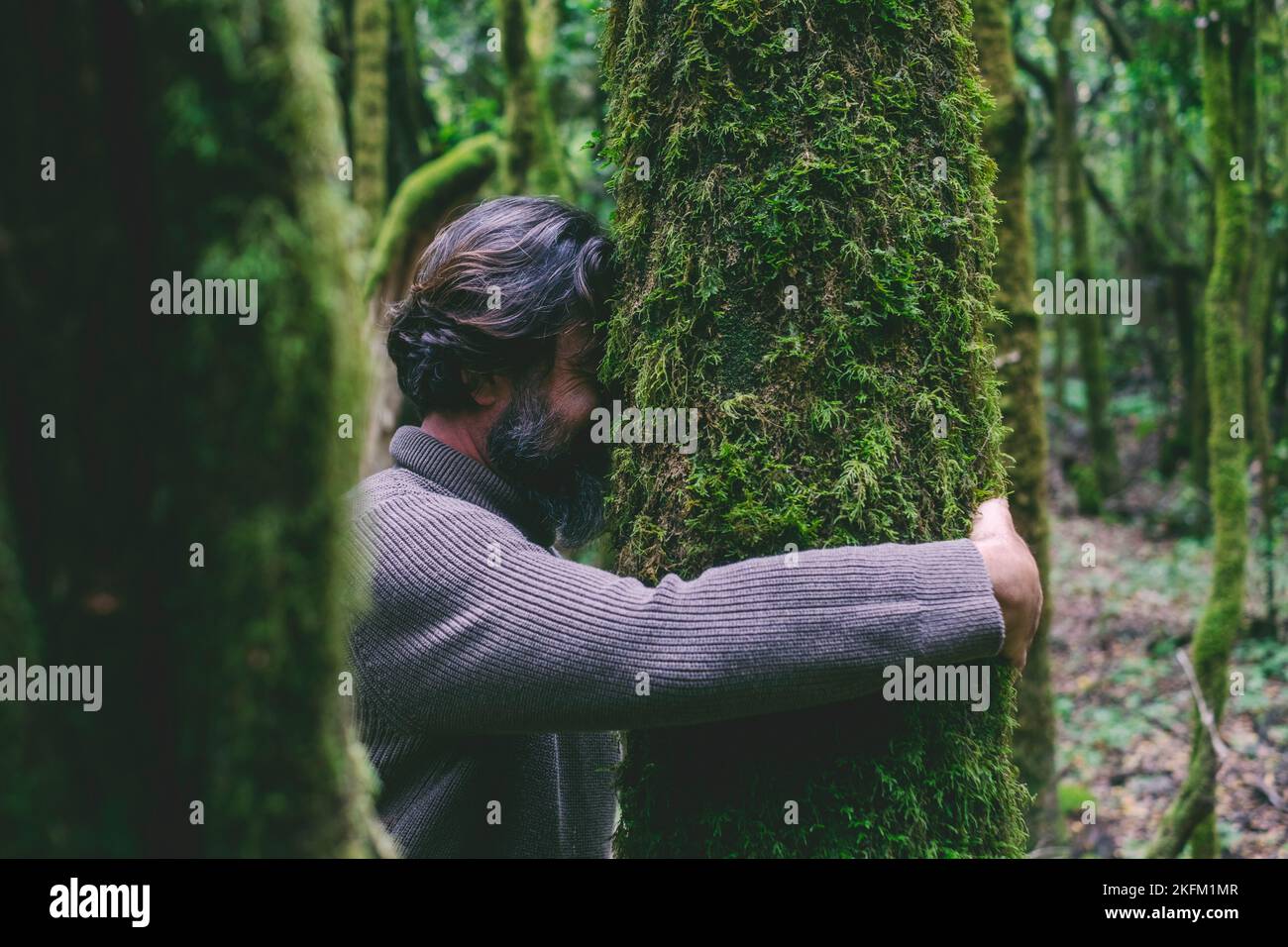 Side view of a man hugging a tree with green musk. Concept of people nature lover and environment. Climate change and global warming stop. Earth's day Stock Photo