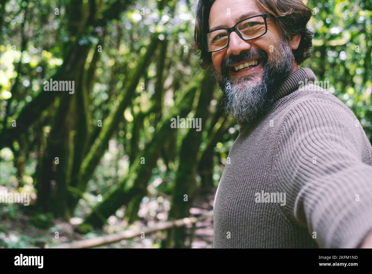 Pov view of man smiling and having fun with green nature trees and forest in background. People enjoying national park woods with friends or alone. En Stock Photo