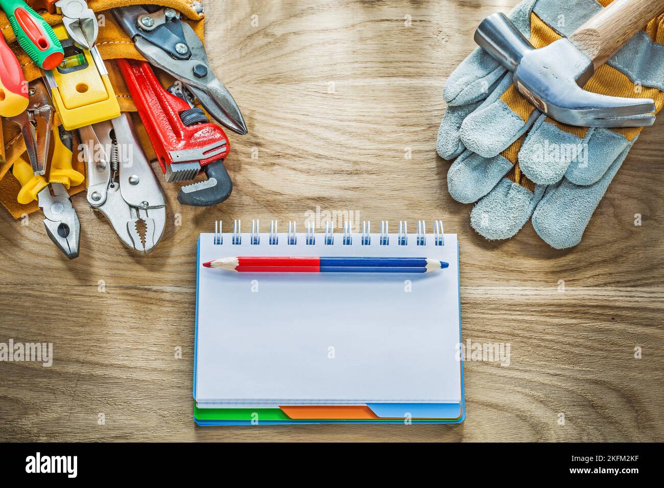 Construction tooling tool belt protective gloves claw hammer notebook pencil. Stock Photo