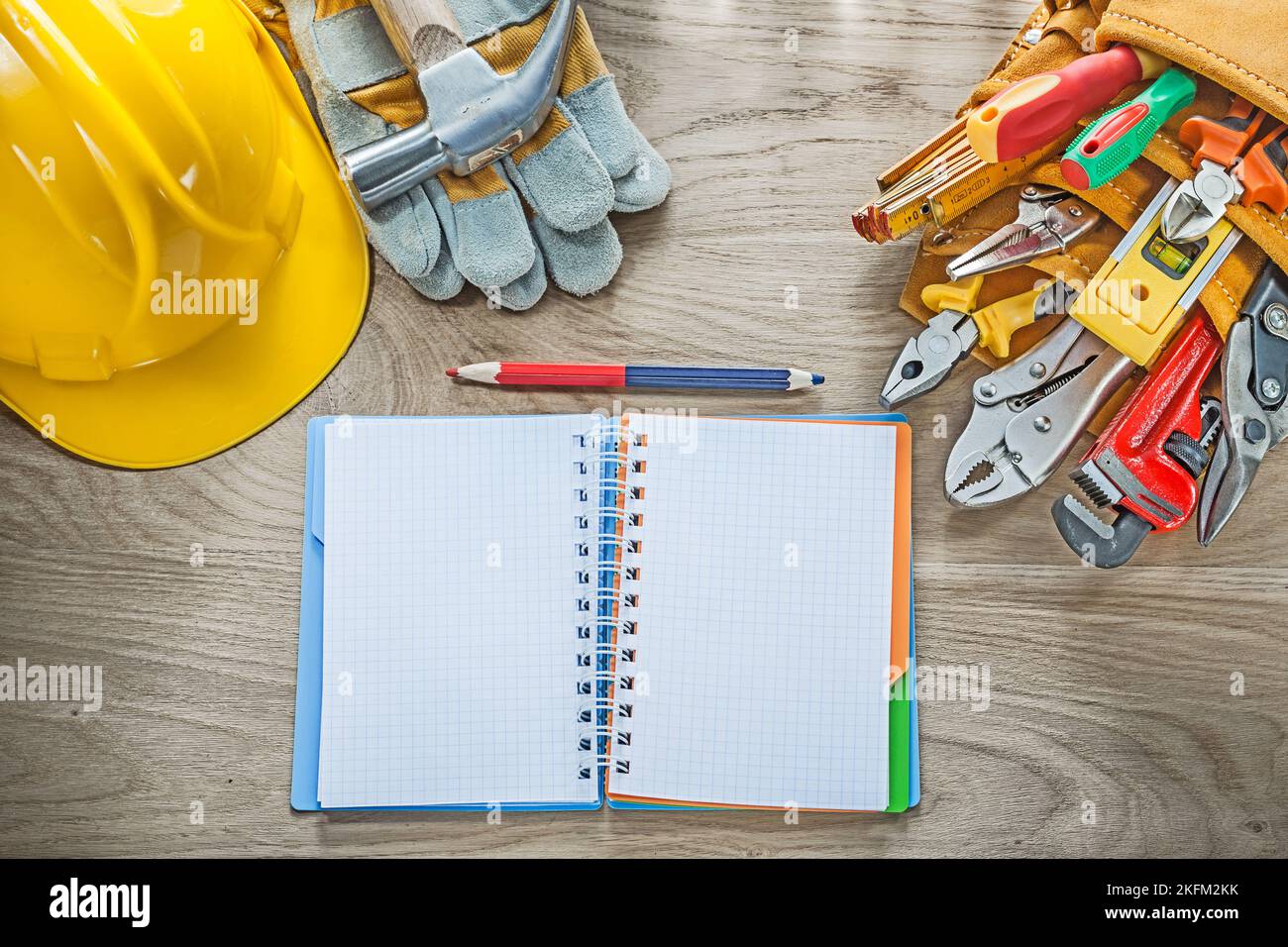 Construction tooling tool belt protective gloves claw hammer notepad pencil hard hat. Stock Photo