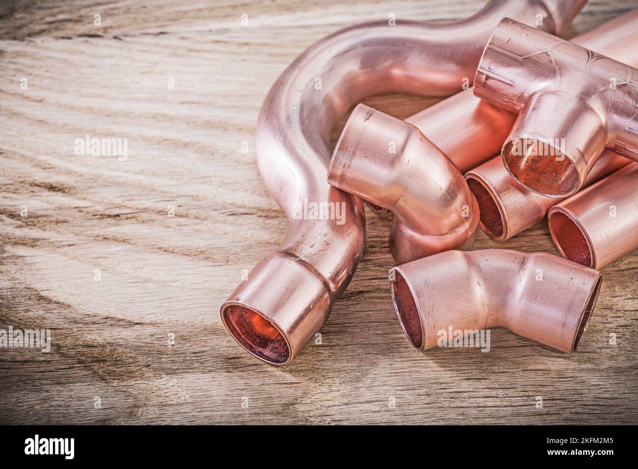 Copper water pipe connectors on wooden board plumbing brassware concept ...