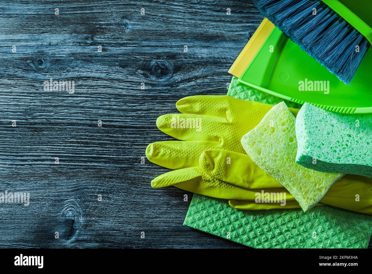 Dustpan brush sponges safety gloves washcloth on wooden board. Stock Photo