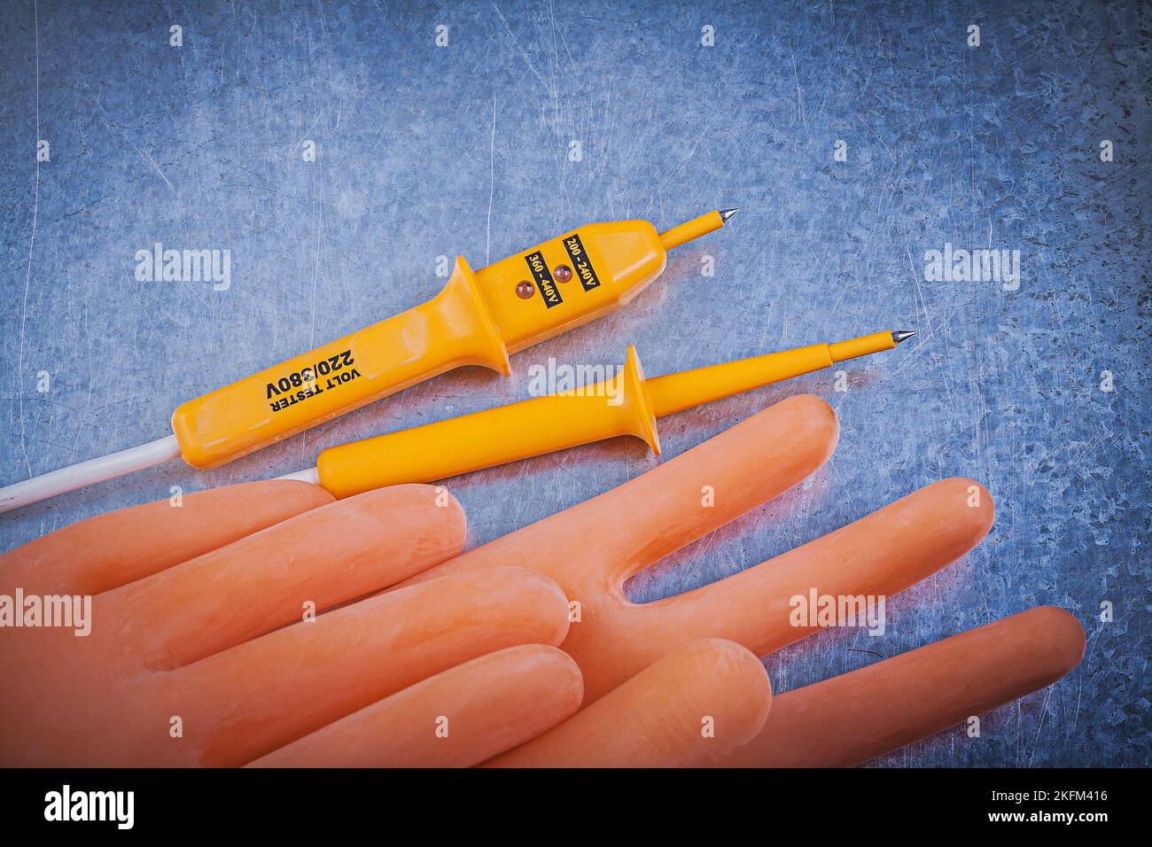 Electricians rubber gloves electric tester on metallic background electricity concept Stock