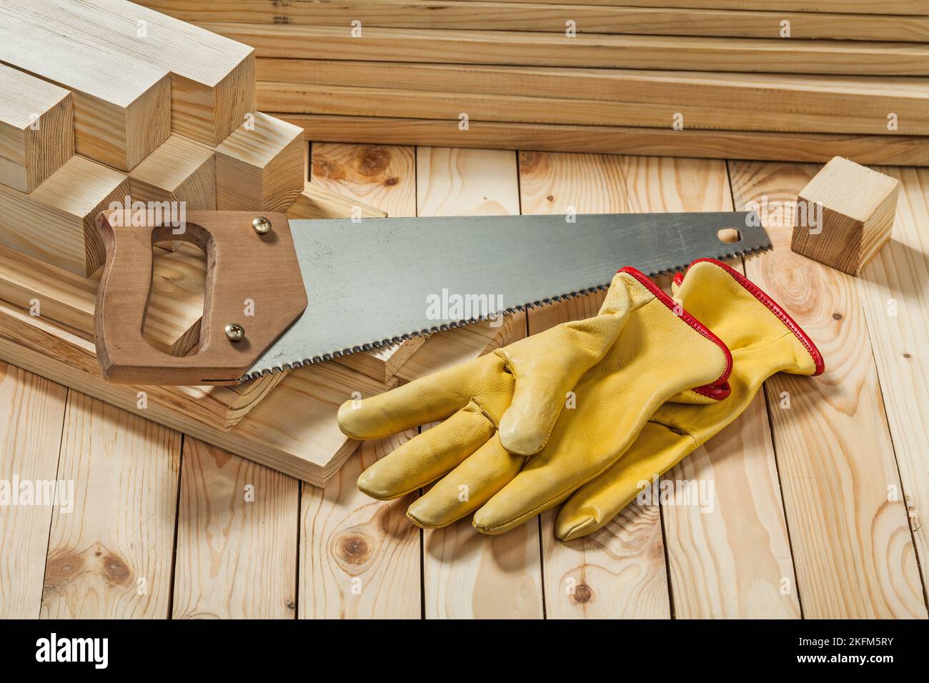 handsaw and yellow working gloves on wooden timber materials Stock Photo