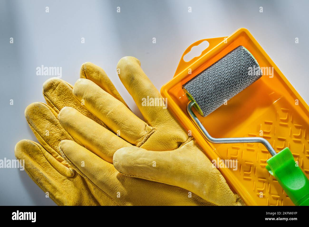Leather safety gloves paint tray roller on white surface Stock Photo