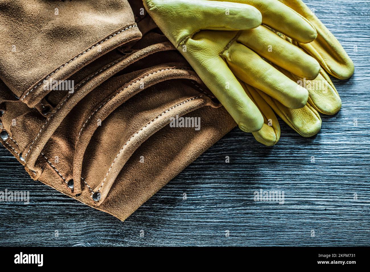Leather tool belt safety gloves on wooden board. Stock Photo