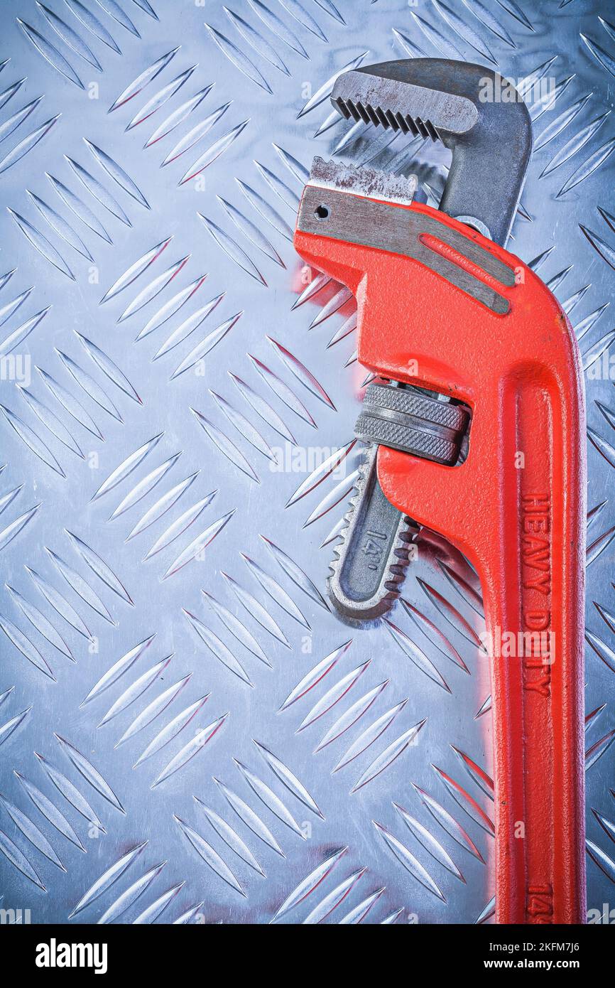 Metal adjustable pipe wrench on fluted metallic sheet vertical view ...