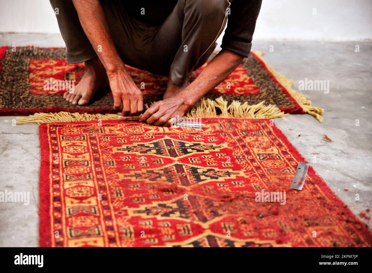 Carpets factory worker busy in the finishing process of handmade
