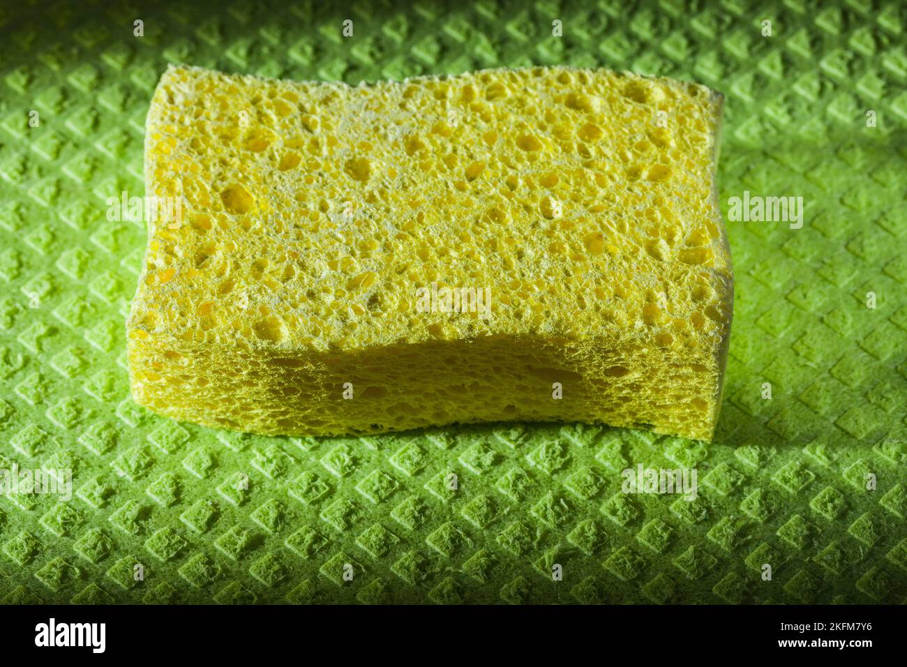 New yellow sponge on green washcloth. Stock Photo