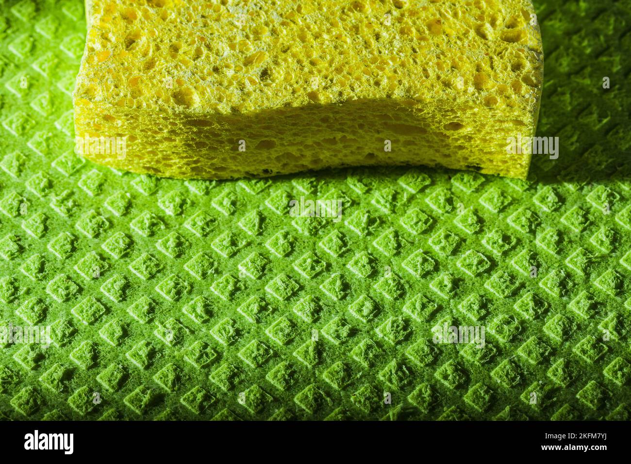 New yellow sponge on green dishcloth. Stock Photo