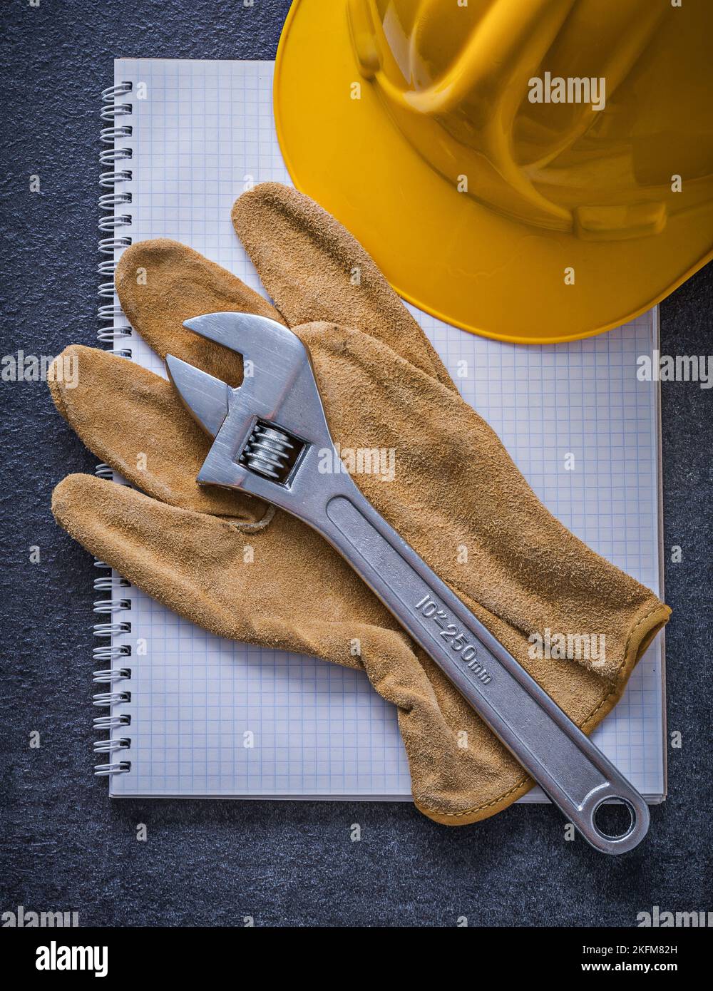 Notebook hard hat adjustable wrench leather working gloves construction concept. Stock Photo