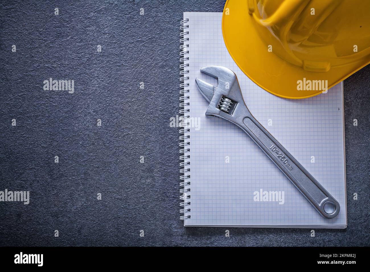 Notebook hard hat adjustable wrench construction concept. Stock Photo