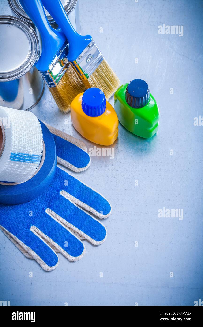 Paint cans bottles brushes duct tapes and protective gloves on metallic