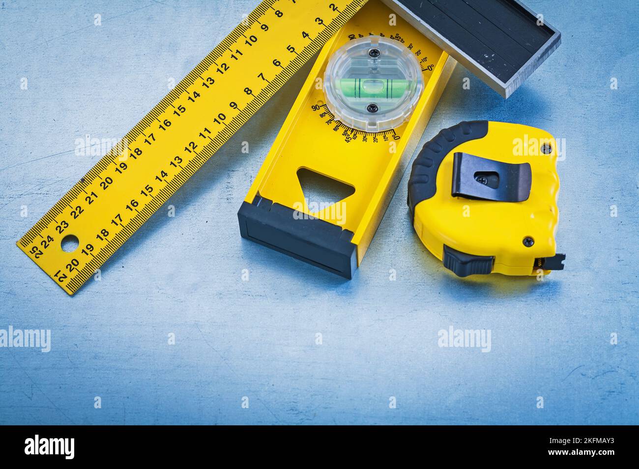 Plastic tape measure wooden construction level and square ruler on metallic background
