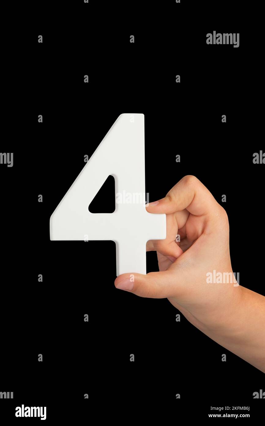 Number four in hand isolated on black background. Number four in a child's hand, holding on a black background. To be inserted into a project or Stock Photo