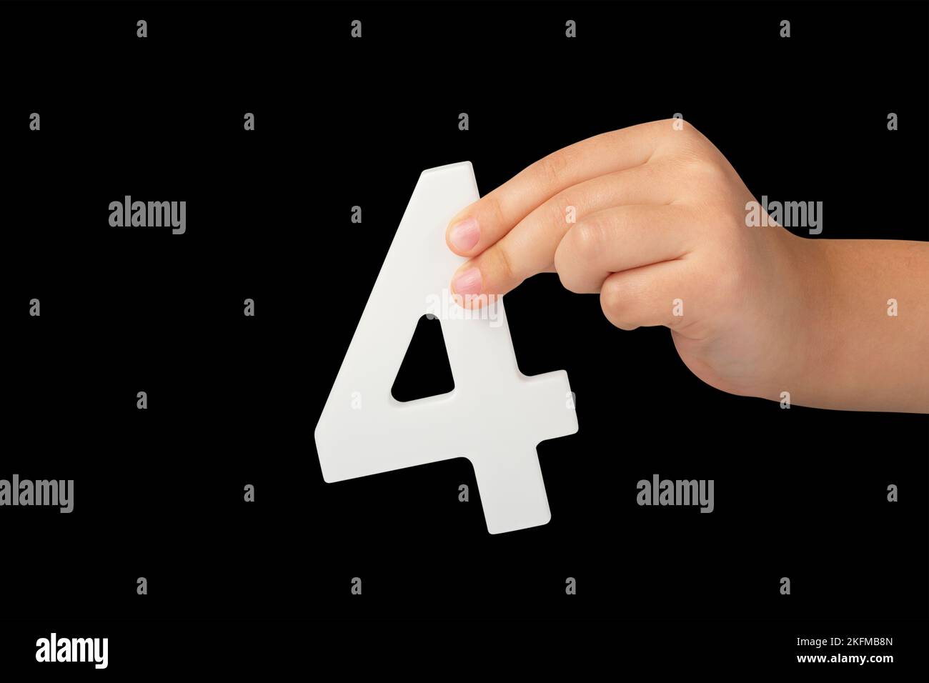 Number four in hand isolated on black background. Number four in a child's hand, holding on a black background. To be inserted into a project or Stock Photo