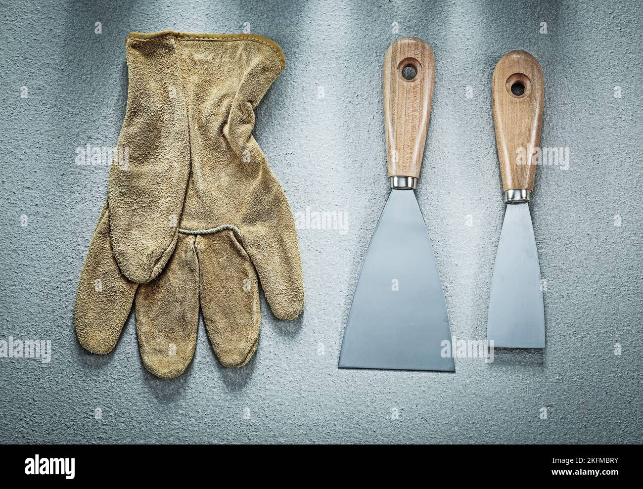 Putty knife safety gloves on concrete surface construction concept