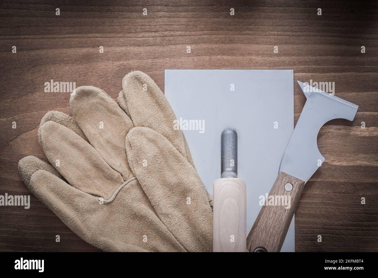 Putty knife plastering trowel and leather working gloves. Stock Photo