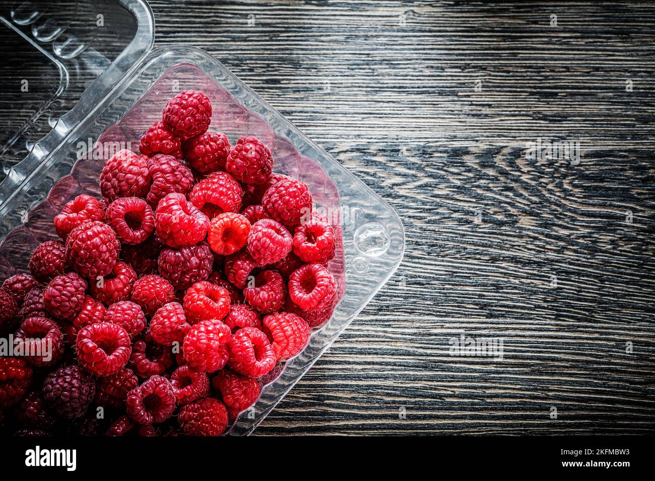 Raspberry in container on wooden board Stock Photo - Alamy